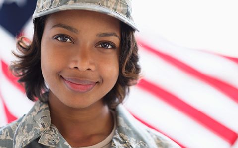Headshot of a woman wearing military uniform standing in front of the American flag.