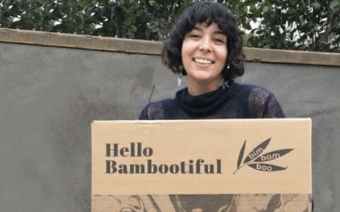 Woman smiling with a sign that reads \"Hello Bambootiful.\"